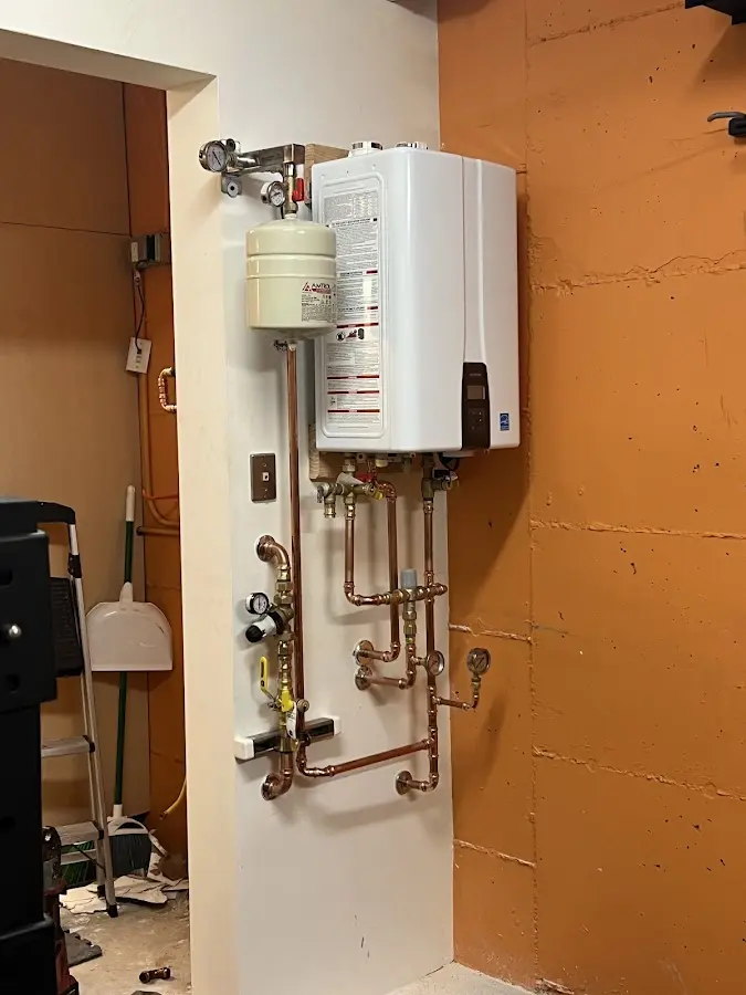 Plumbing technician inspecting water heater connections in West Branch
